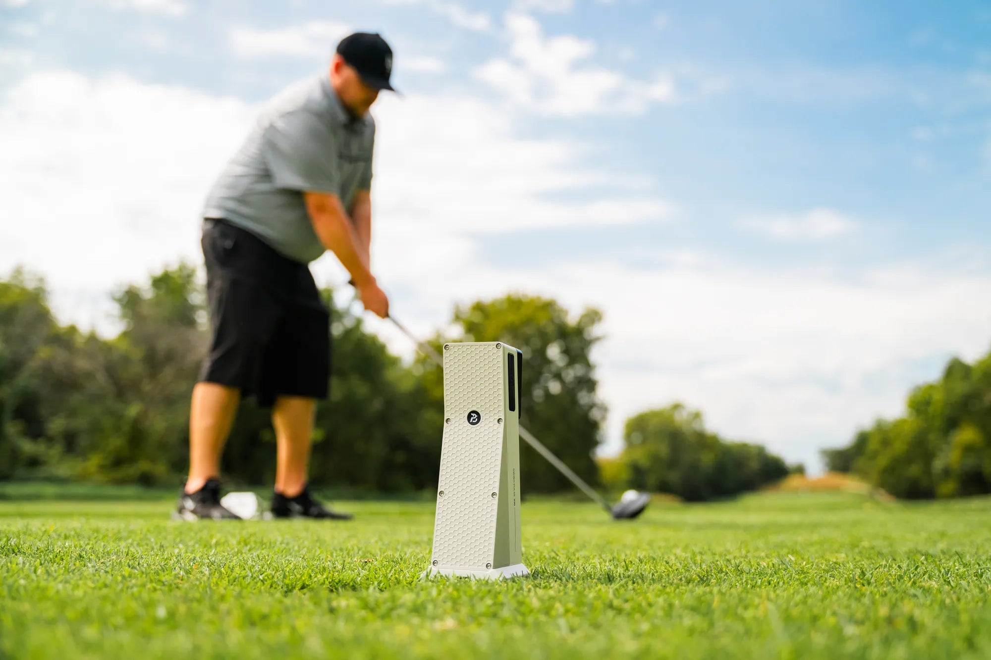 Golfer finishing a drive with the X10 set up on the tee